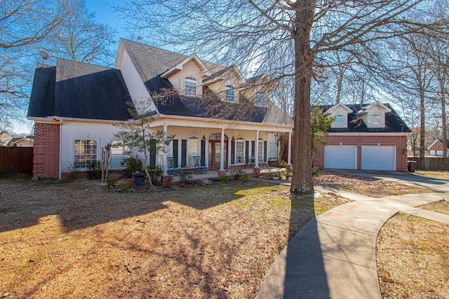 cape cod-style house featuring a garage, covered porch, and a front yard