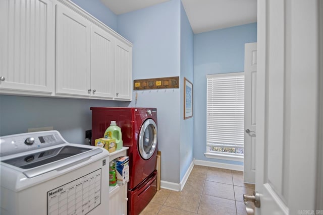 laundry room featuring washer and dryer, cabinets, and light tile patterned flooring