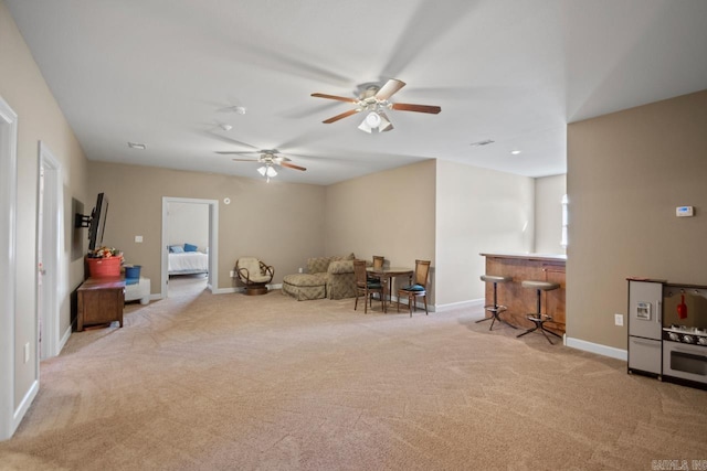 interior space with light carpet, bar area, and ceiling fan