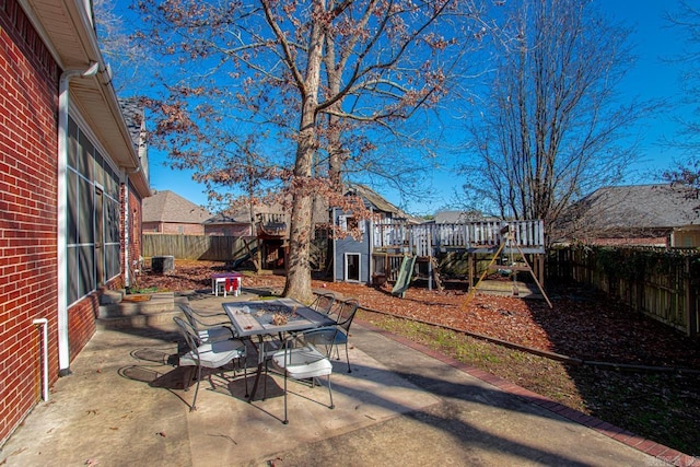 view of patio featuring a playground, a wooden deck, and central AC unit