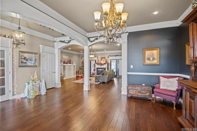 entryway featuring dark hardwood / wood-style flooring, decorative columns, an inviting chandelier, and ornamental molding