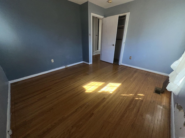 unfurnished bedroom with dark hardwood / wood-style floors and a closet