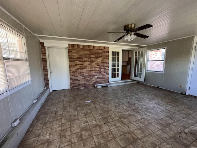 unfurnished sunroom featuring ceiling fan and french doors