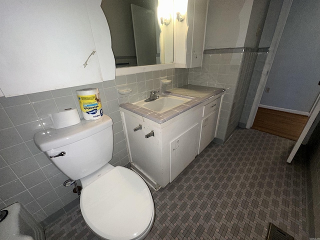 bathroom with vanity, tasteful backsplash, toilet, and tile walls