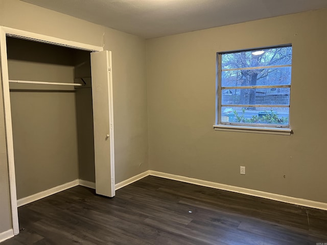 unfurnished bedroom with dark hardwood / wood-style floors and a closet