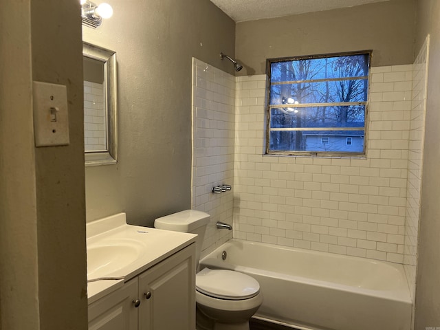 full bathroom featuring vanity, tiled shower / bath combo, a textured ceiling, and toilet