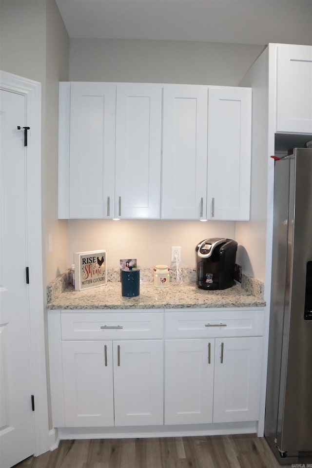 bar with stainless steel fridge, dark hardwood / wood-style floors, white cabinetry, and light stone counters