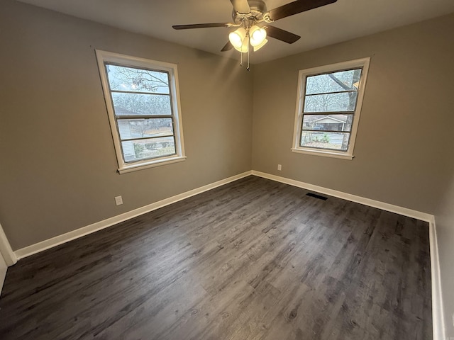 empty room with ceiling fan, dark hardwood / wood-style flooring, and a wealth of natural light