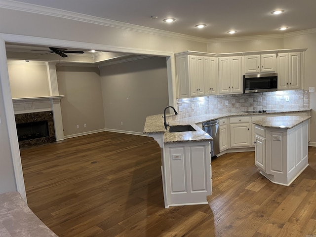 kitchen featuring sink, stainless steel appliances, backsplash, kitchen peninsula, and white cabinets