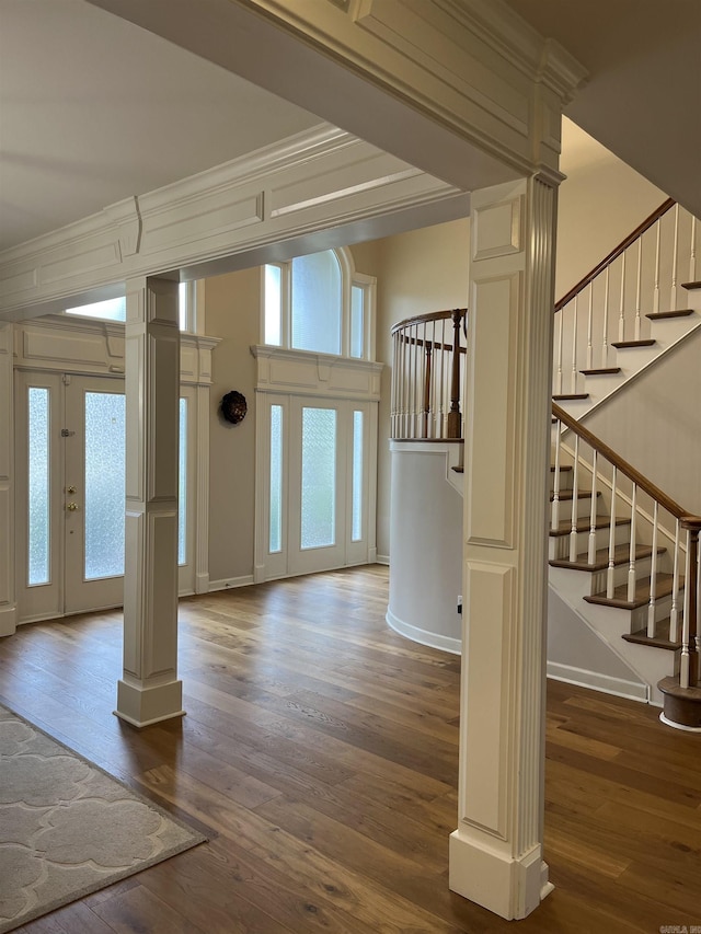 entryway with dark hardwood / wood-style floors, crown molding, and decorative columns