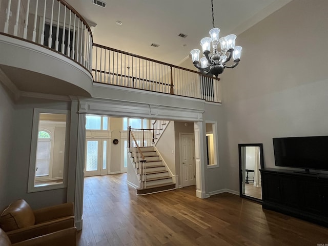 unfurnished living room featuring a chandelier, a high ceiling, and hardwood / wood-style floors