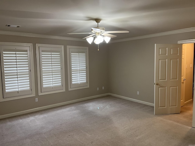 unfurnished room featuring ceiling fan, light colored carpet, crown molding, and a wealth of natural light