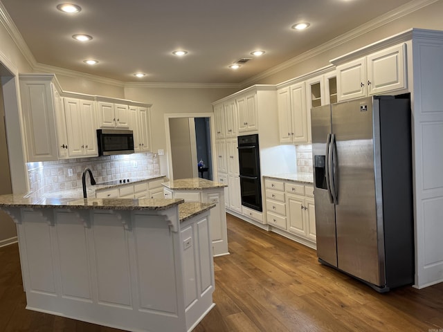 kitchen featuring black appliances, white cabinets, a kitchen bar, and tasteful backsplash