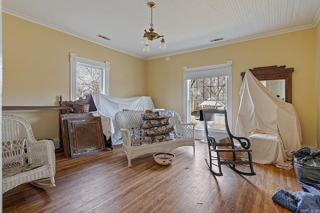 sitting room featuring wood-type flooring, crown molding, and a chandelier