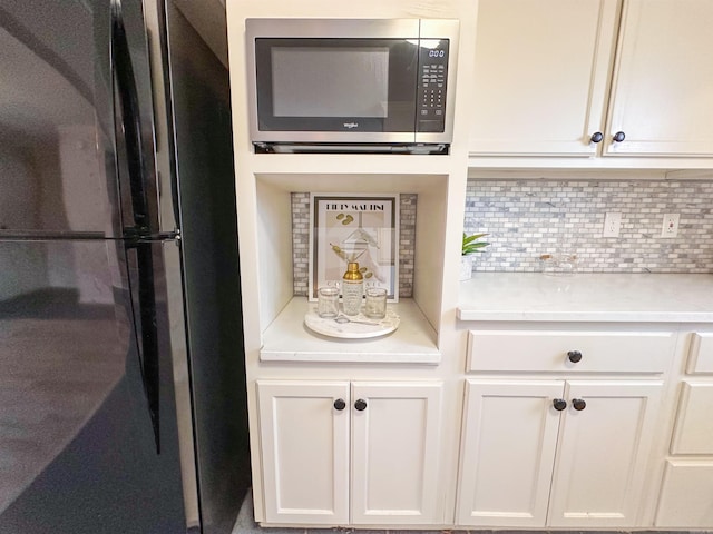 room details with refrigerator, white cabinetry, and tasteful backsplash