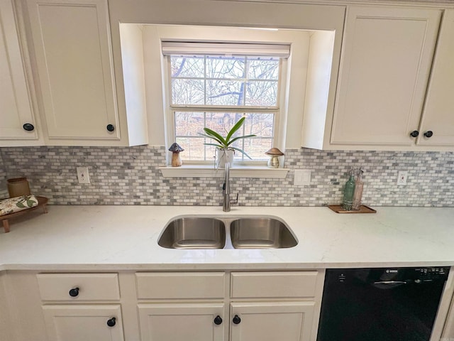 kitchen featuring light stone countertops, decorative backsplash, black dishwasher, and sink