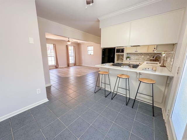 kitchen with built in microwave, ceiling fan, a kitchen breakfast bar, kitchen peninsula, and decorative backsplash