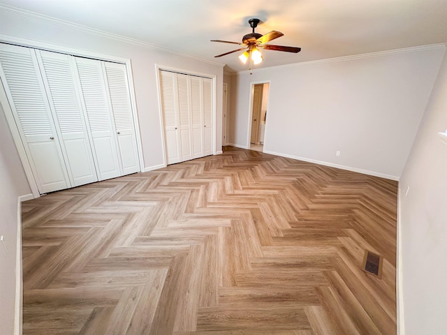 unfurnished bedroom featuring multiple closets, ceiling fan, light parquet flooring, and ornamental molding