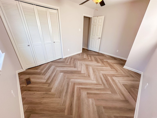 unfurnished bedroom with ceiling fan, light parquet flooring, and a closet