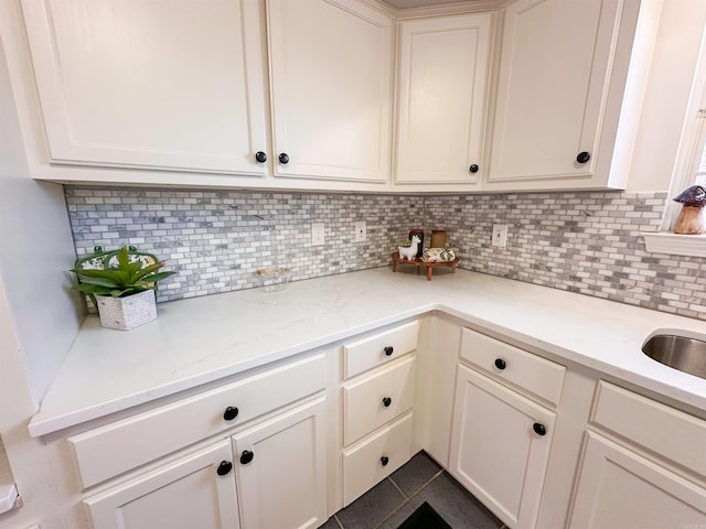 kitchen featuring decorative backsplash, dark tile patterned flooring, and light stone counters