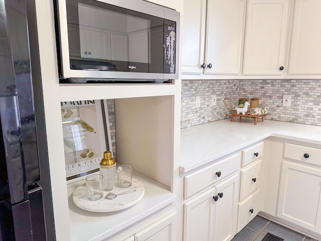 kitchen with backsplash, white cabinetry, and light tile patterned floors