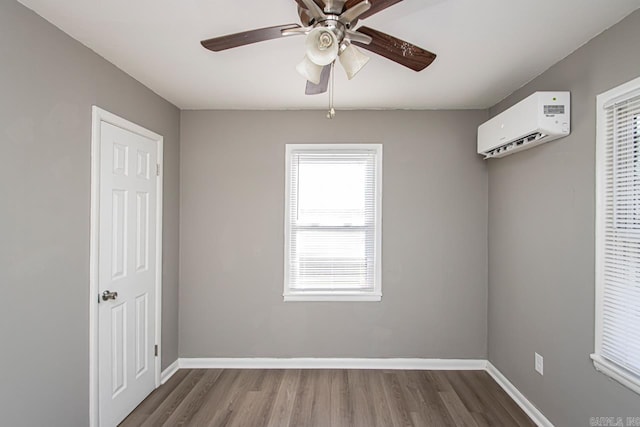 spare room featuring a wall mounted air conditioner, hardwood / wood-style floors, and ceiling fan