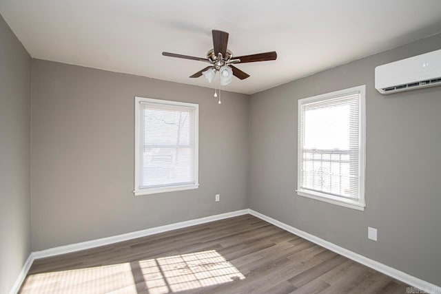 unfurnished room featuring hardwood / wood-style floors, a wealth of natural light, ceiling fan, and a wall unit AC