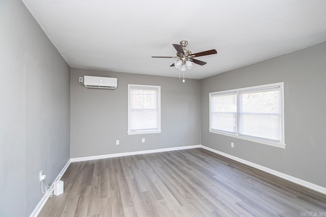 spare room featuring a wall mounted air conditioner, ceiling fan, and light hardwood / wood-style flooring