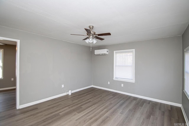 unfurnished room with a wall mounted air conditioner, dark hardwood / wood-style flooring, and ceiling fan