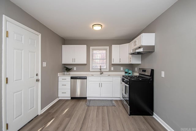 kitchen with wood-type flooring, appliances with stainless steel finishes, white cabinetry, and sink