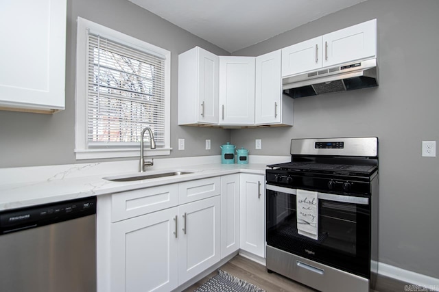 kitchen featuring a wealth of natural light, light stone countertops, sink, white cabinets, and appliances with stainless steel finishes