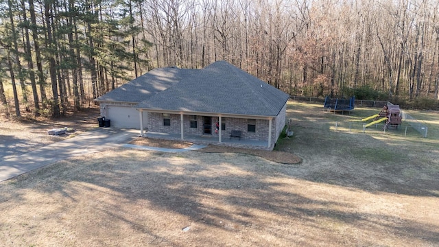 view of front of property featuring a playground, a trampoline, a garage, and covered porch