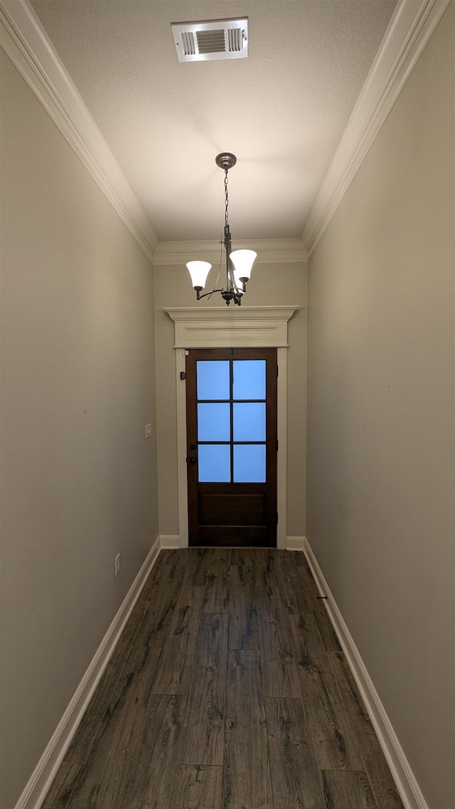 doorway to outside featuring a notable chandelier, crown molding, and dark wood-type flooring