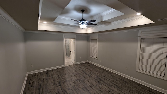 unfurnished bedroom with dark wood-type flooring, a tray ceiling, and crown molding