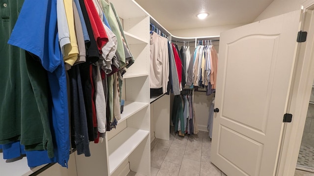 walk in closet with light tile patterned floors