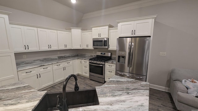 kitchen with sink, appliances with stainless steel finishes, light stone counters, ornamental molding, and white cabinets