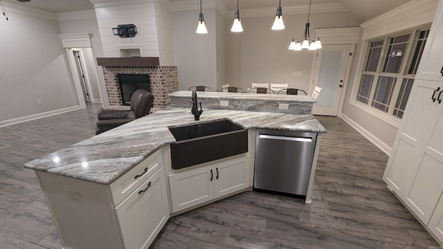 kitchen with decorative light fixtures, dishwasher, sink, white cabinets, and a kitchen island with sink