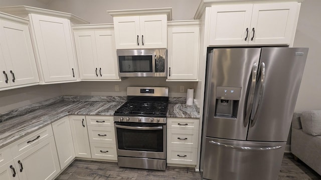 kitchen with stainless steel appliances, white cabinetry, dark hardwood / wood-style floors, and dark stone countertops