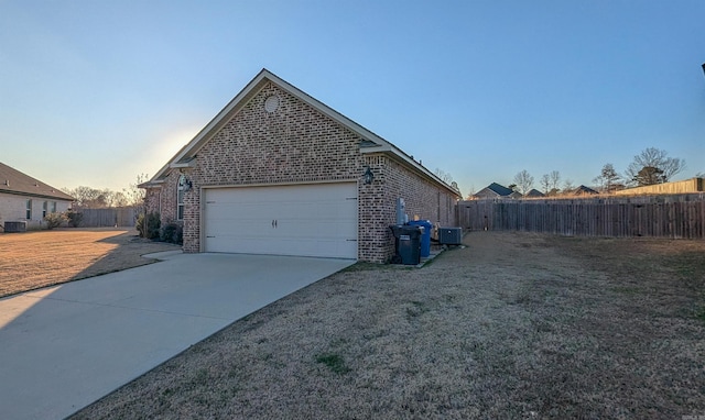 property exterior at dusk with a garage, a yard, and central AC