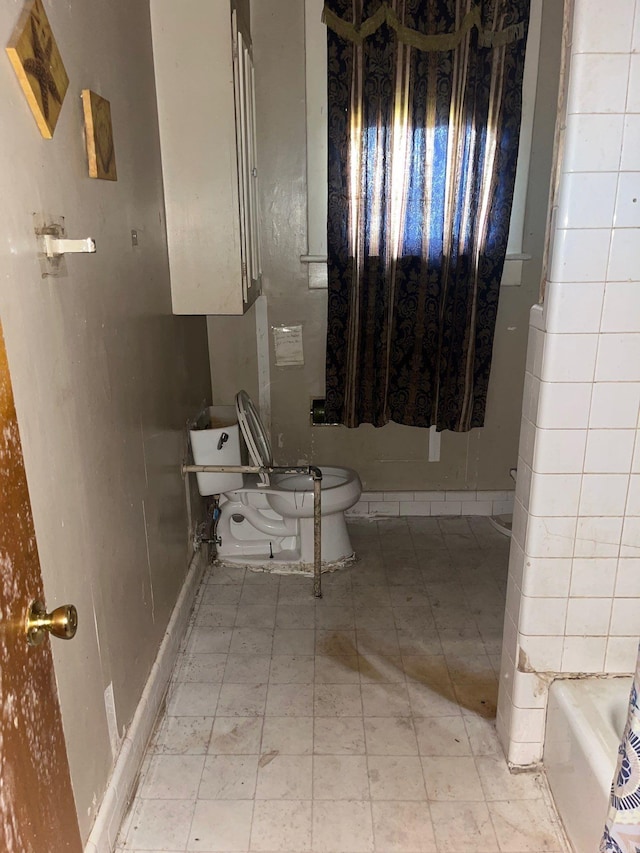 bathroom with a tub to relax in and toilet