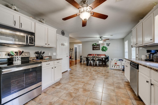 kitchen with white cabinetry, stainless steel appliances, light tile patterned floors, and dark stone counters