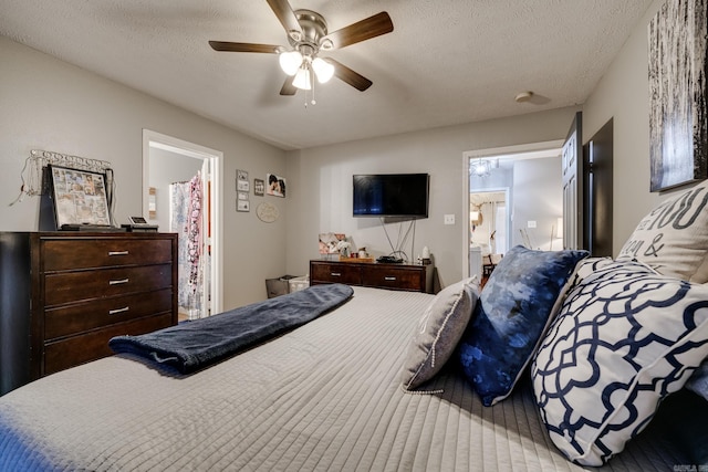 bedroom with ceiling fan, a textured ceiling, and connected bathroom