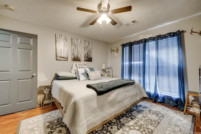 bedroom featuring ceiling fan, wood-type flooring, and a textured ceiling