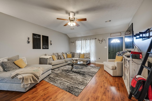 living room with wood-type flooring, a textured ceiling, ceiling fan, and lofted ceiling