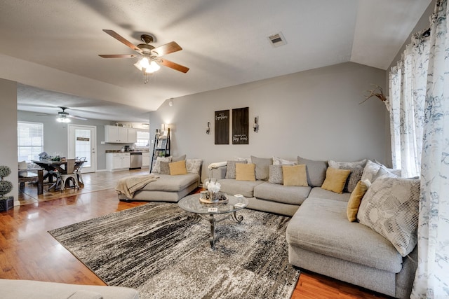 living room with hardwood / wood-style floors, ceiling fan, and lofted ceiling