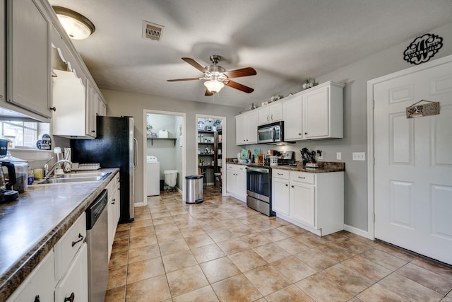 kitchen with appliances with stainless steel finishes, white cabinetry, washer / dryer, and sink