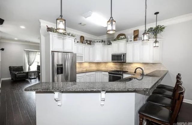 kitchen featuring a kitchen bar, kitchen peninsula, hanging light fixtures, and appliances with stainless steel finishes