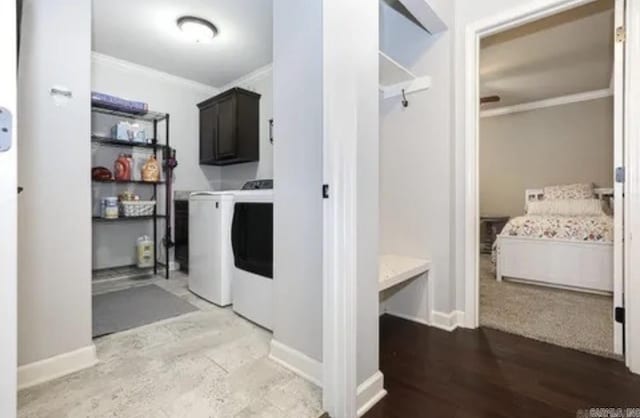 clothes washing area featuring washer and clothes dryer, cabinets, and crown molding