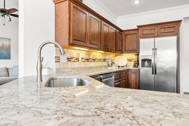 kitchen with light stone counters, sink, stainless steel appliances, and crown molding