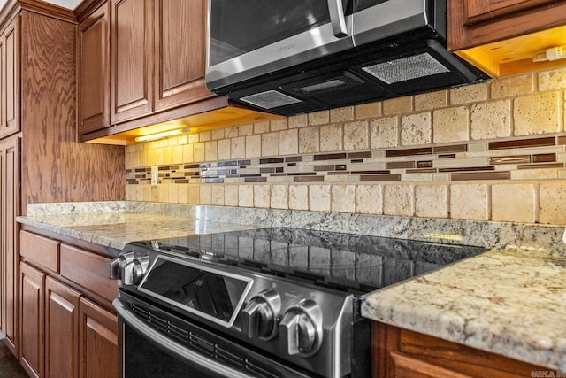 kitchen with tasteful backsplash, light stone countertops, and stainless steel appliances